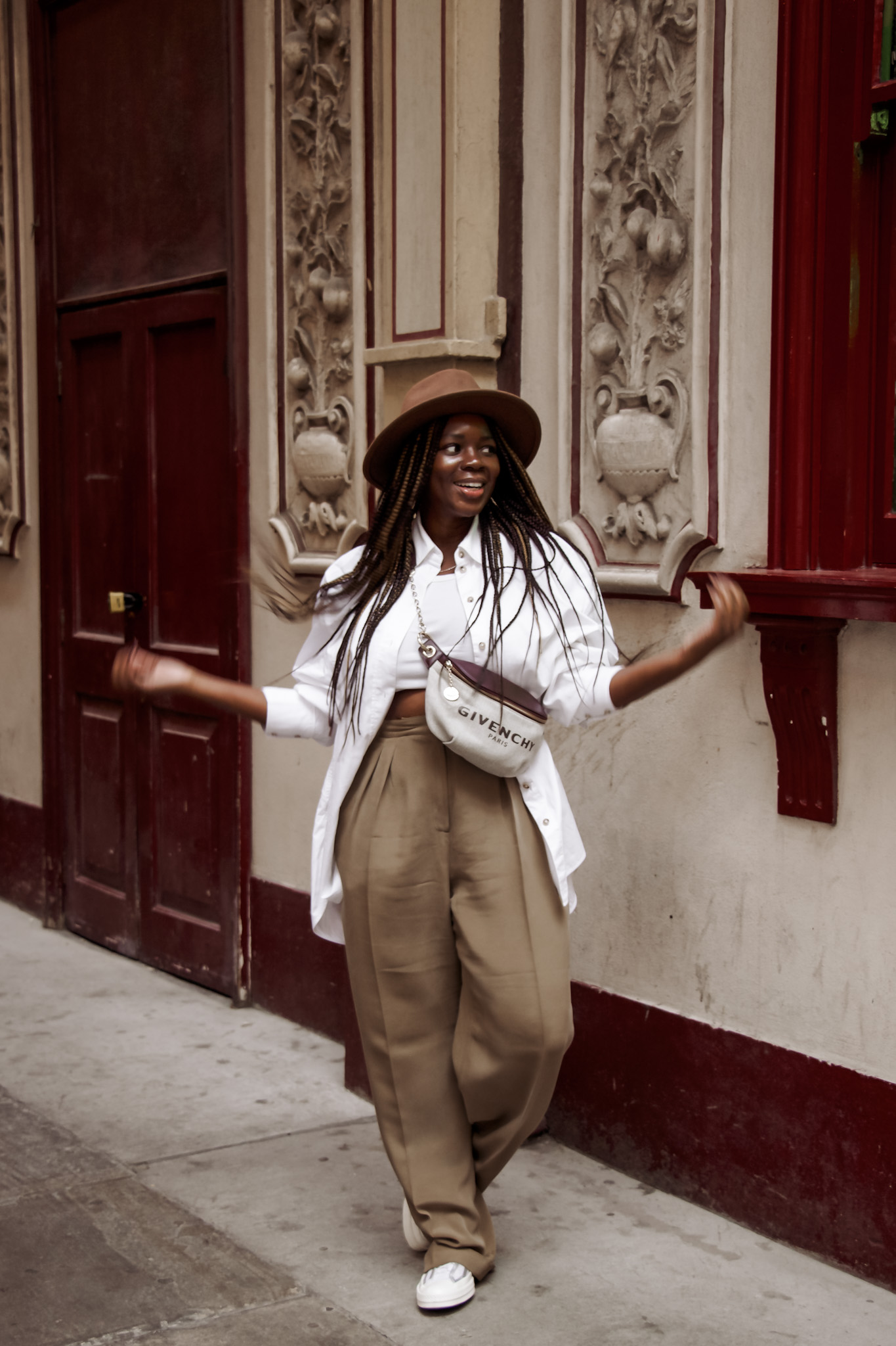 black woman in alley touching white beret